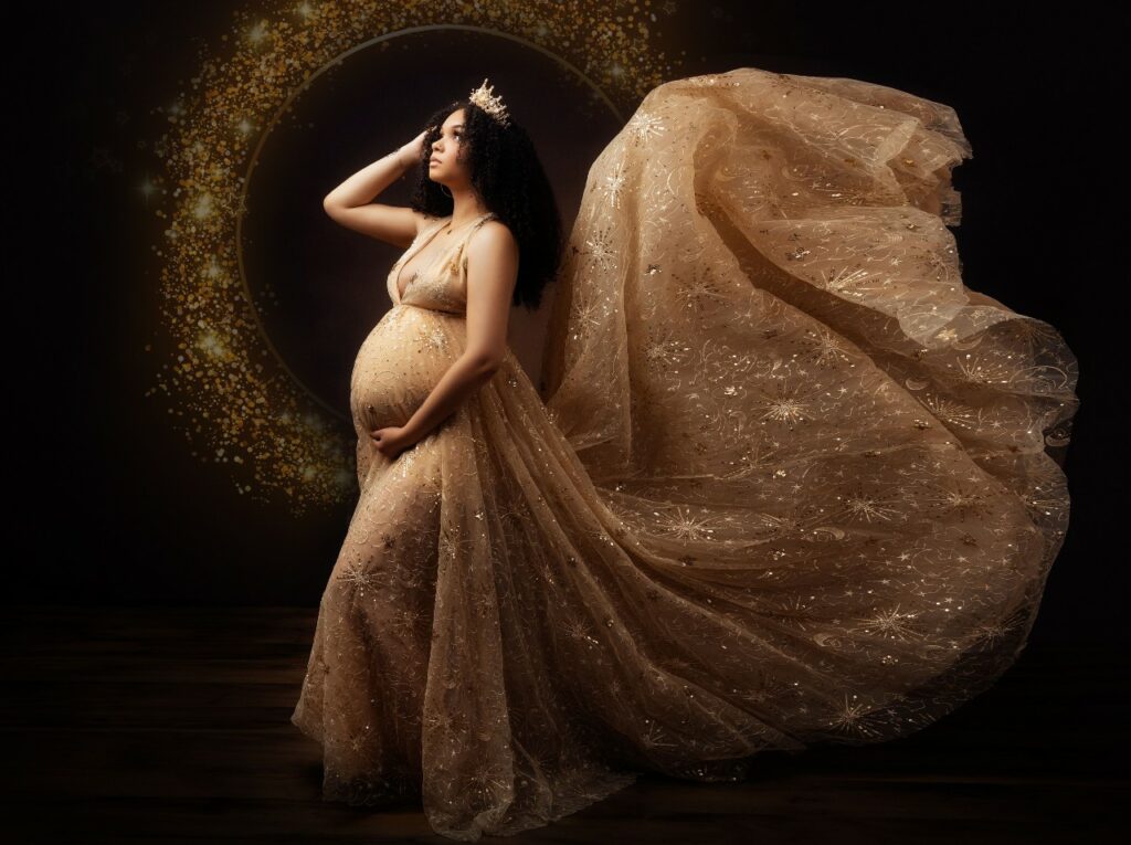 Pregnant woman posing in flying gold metallic maternity gown